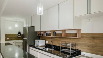 A modern kitchen with a stainless steel refrigerator, a microwave, and a sink with a metal drying rack.