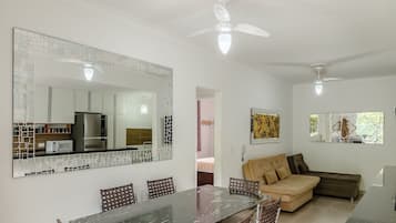 A modern living space with a dining area, kitchen, and a sofa.