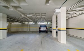 Eine leere Parkgarage mit Betonböden, weißen Wänden und gelb-schwarz gestreiften Markierungen.