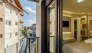 Ein modernes Hotelzimmer mit Balkon, einem Bett, einem Fernseher und einer kleinen Sitzecke.