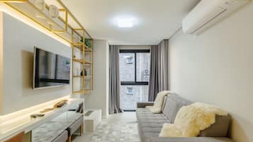 Una sala de estar moderna con un televisor de pantalla plana, un sofá y una mesa de centro.