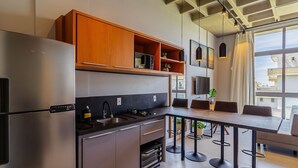 Eine moderne Küche mit einem eingebauten Kühlschrank, Holzschränken, einer Bar mit Hockern und einem großen Fenster mit Blick auf die Stadt.