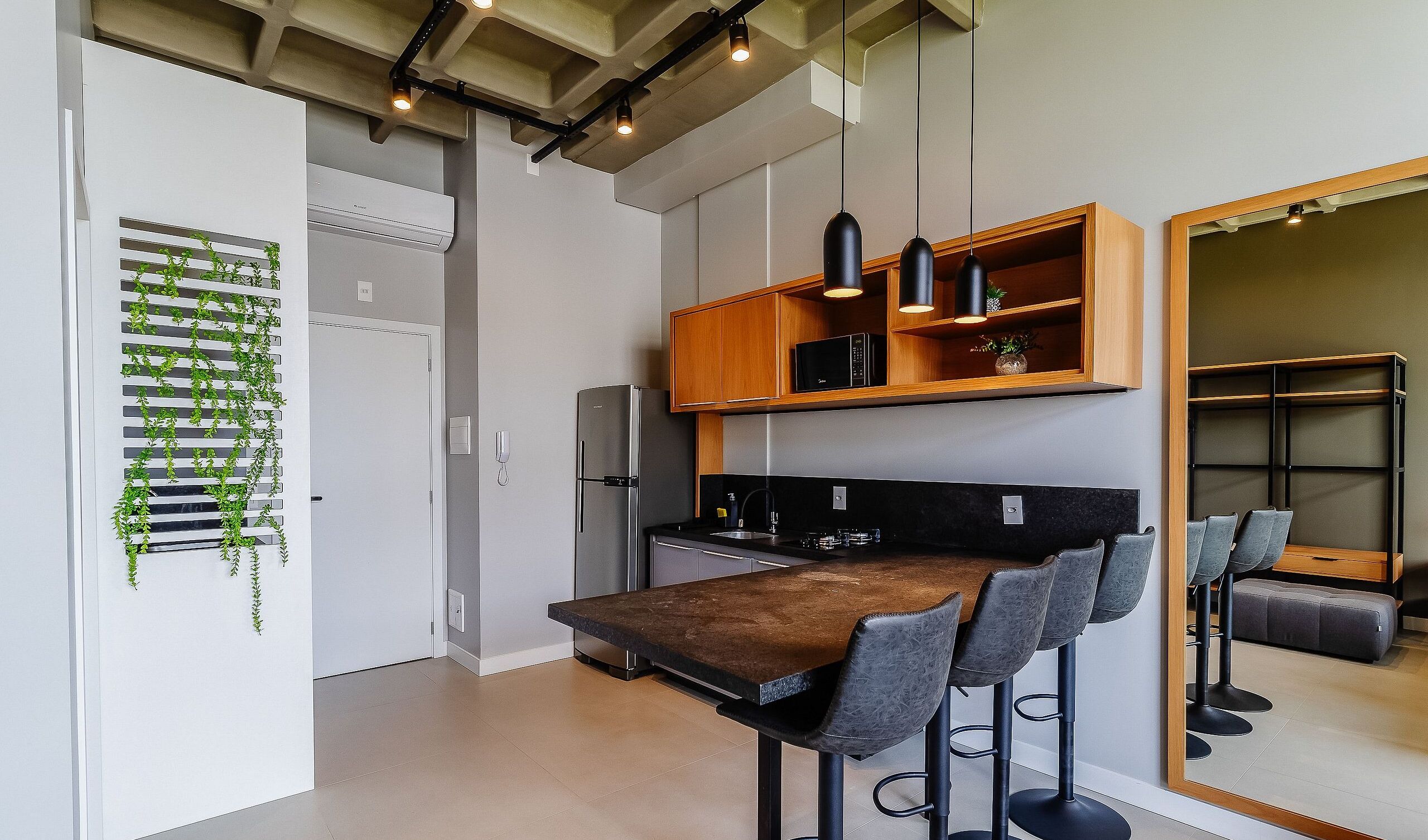 A modern kitchen with a built-in refrigerator, a wooden countertop, and a bar area with bar stools.