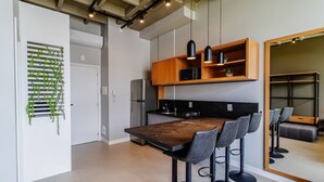 Eine moderne Küche mit einem eingebauten Kühlschrank, einer Holz Arbeitsplatte und einer Bar mit Barhocker.