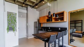 A modern kitchen with a built-in refrigerator, a wooden countertop, and a bar area with bar stools.