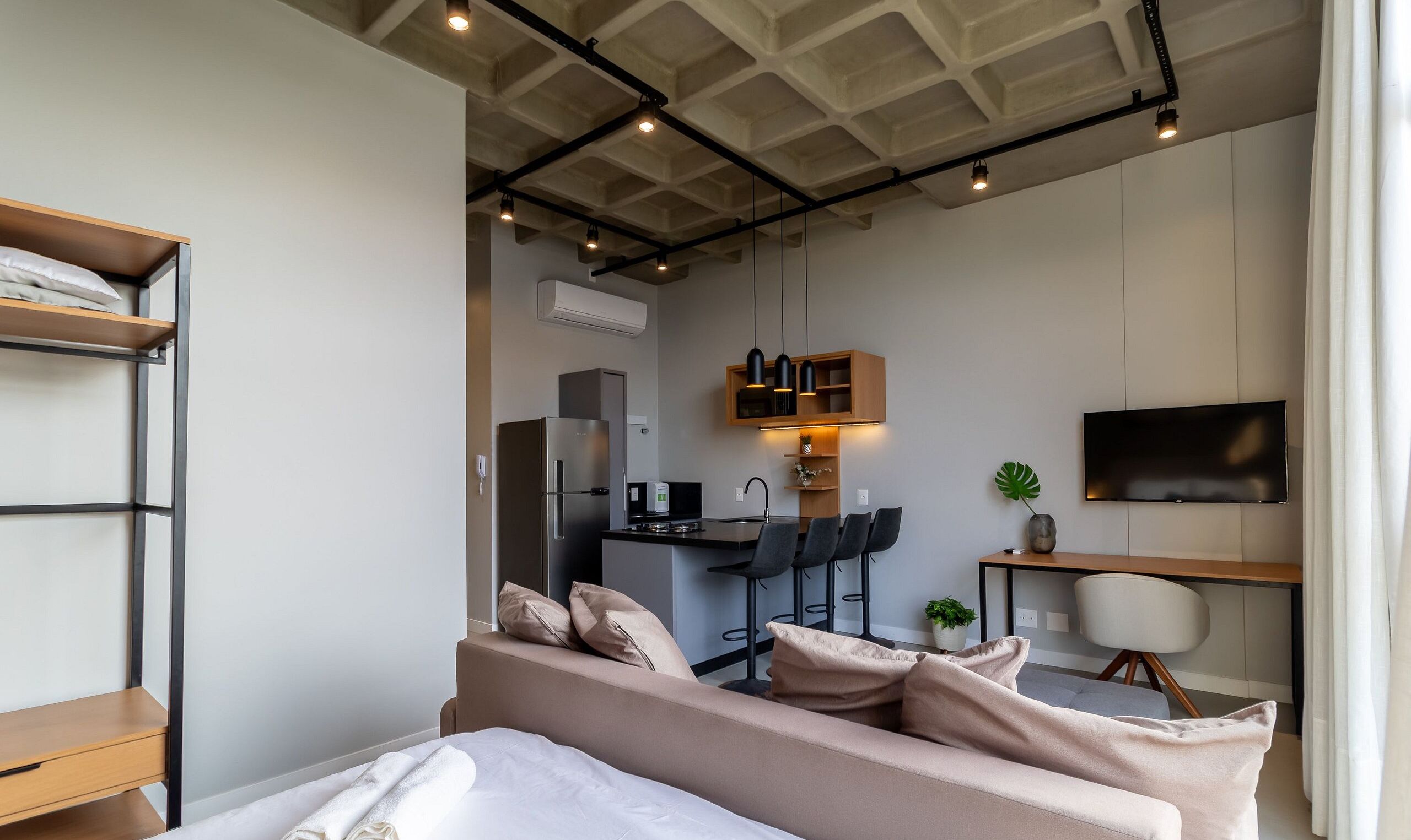 Une chambre d’hôtel moderne équipée d’un lit, d’un bureau, d’une télévision et d’une kitchenette.