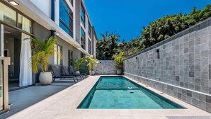 A modern outdoor pool area with a clear blue pool, lounge chairs, and potted plants. - Amazing Studio 750m From Canas Beach Tps105 (Florianópolis)