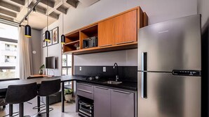 A modern kitchen with a stainless steel refrigerator, wooden cabinets, and a built-in oven. - Amazing Studio 750m From Canas Beach Tps105 (Florianópolis)