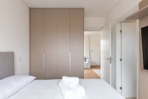 A neatly made bed with white linens and towels, a grey headboard, and a large wardrobe with sliding doors. - Functional Apt w/ Garage in Curitiba Wsh0801 (Curitiba)