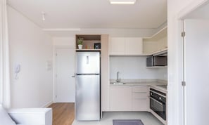 A compact kitchen with a built-in refrigerator, microwave, oven, and sink. - Functional Apt w/ Garage in Curitiba Wsh0801 (Curitiba)