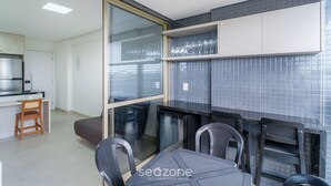 A modern kitchen with a dining area, featuring a built-in oven, a refrigerator, and a glass partition. - Seafront apt in Ondina, With Balcony - Bca2004 (Salvador)