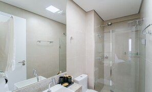 Ein modernes Badezimmer mit einer Duschkabine, einem großen Spiegel und einem Waschbecken mit Marmorplatte.