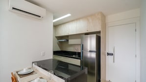 Eine kleine Küche mit Einbauofen, Edelstahlkühlschrank und Mikrowelle.