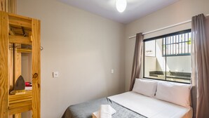 A hotel room with a bed, a window with curtains, a wooden wardrobe, and a ceiling light. - 2BR House w/ BBQ 270m From Beach Ruc0002 (Bombinhas)