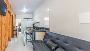 Una cocina moderna con estufa integrada, taburetes de bar y un sofá de cuero negro.