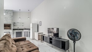 En moderne stue med en sofa, et fjernsyn og en gulvventilator.
