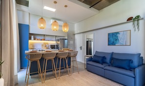 A modern kitchen with a central island, bar stools, and a blue sofa in a living area. - Studio With Pool 750m From the Beach Tps0206 (Florianópolis)