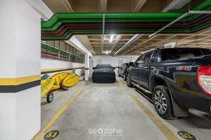 A parking garage with a yellow kayak, a black SUV, and a black car parked. - Apt in Resort w/ Pool 200m From the Beach Mhe0114 (Florianópolis)