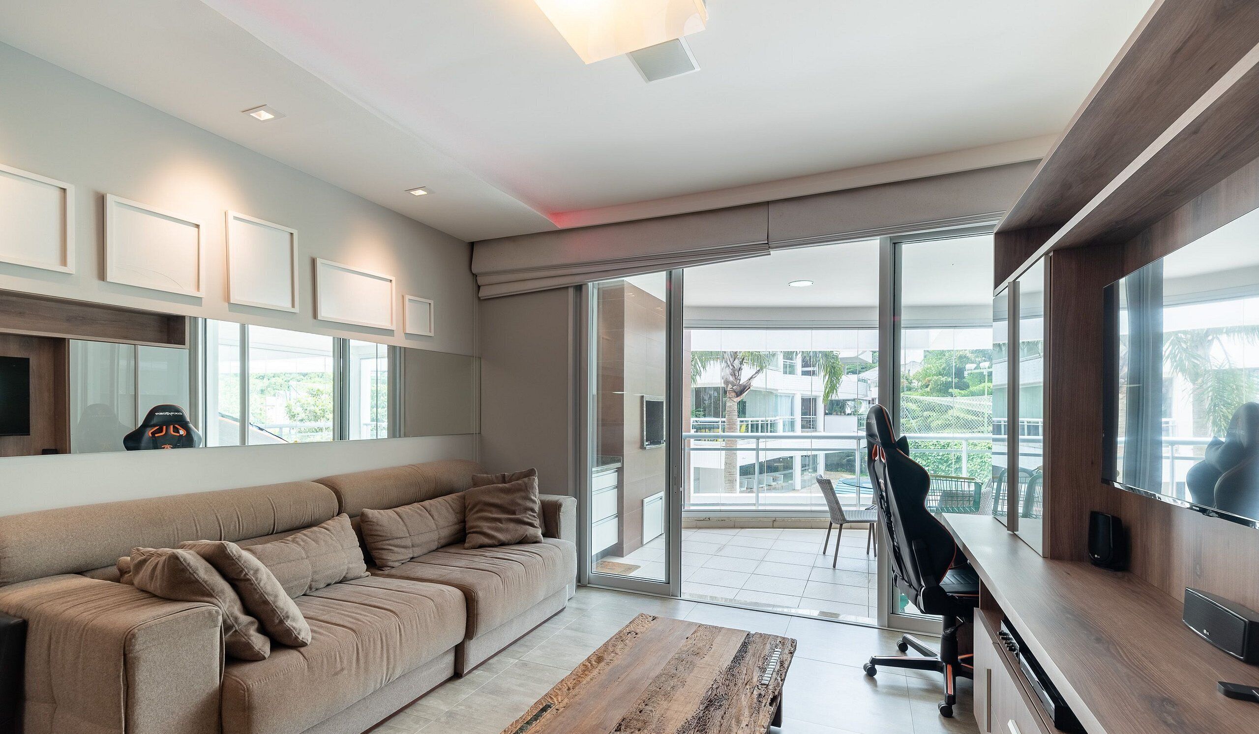 A modern living room with a sofa, a desk with a chair, a large window, and a balcony.