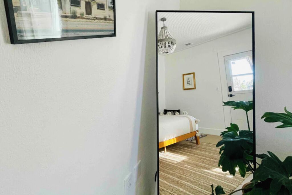 Ein Schlafzimmer mit Bett, einer Pendelleuchte, einer Tür und einem Fenster.