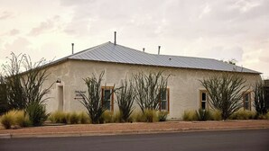 A building with a metal roof, a sign indicating '2006 Russell Entrance,' and a landscaped area with desert plants. - Bohemio Rebel: Sauna, Pickleball + Walkable Marfa (Marfa)