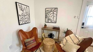 A living room with two leather chairs, a small table with a plant, and two framed artworks on the wall. - Bohemio Rebel: Sauna, Pickleball + Walkable Marfa (Marfa)