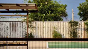 A tennis court with a metal fence and trees in the background.