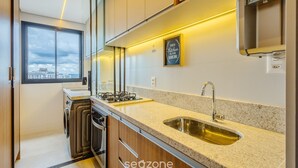Una cocina moderna con un amplio ventanal, un lavamanos de acero inoxidable y una estufa a gas.
