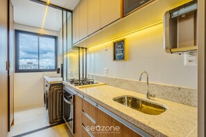 A modern kitchen with a large window, a stainless steel sink, and a gas stove. - Modern and Complete Stay in Brasilia - Epk0903 (Guará)