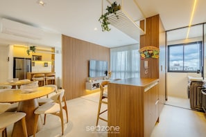A modern kitchen with wooden cabinetry, a central island, and a built-in oven. - Modern and Complete Stay in Brasilia - Epk0903 (Guará)