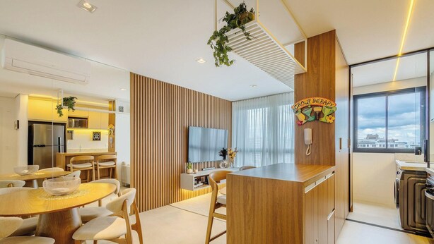 Una cocina moderna con horno integrado, un comedor con mesa redonda y sillas, y un ventanal con vista a la ciudad.