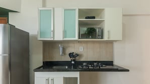 A kitchen with white cabinets, a black countertop, a stainless steel refrigerator, and a microwave. - Apt in Cond. w/ Pool, Steps fr the Beach Esn0702 (Salvador)