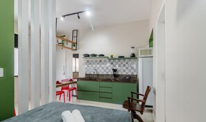 A compact kitchen with green cabinets, a countertop, and a refrigerator. There is a dining area with a table and chairs. - Studio the City Center 300m Pelourinho Hai0203 (Salvador)