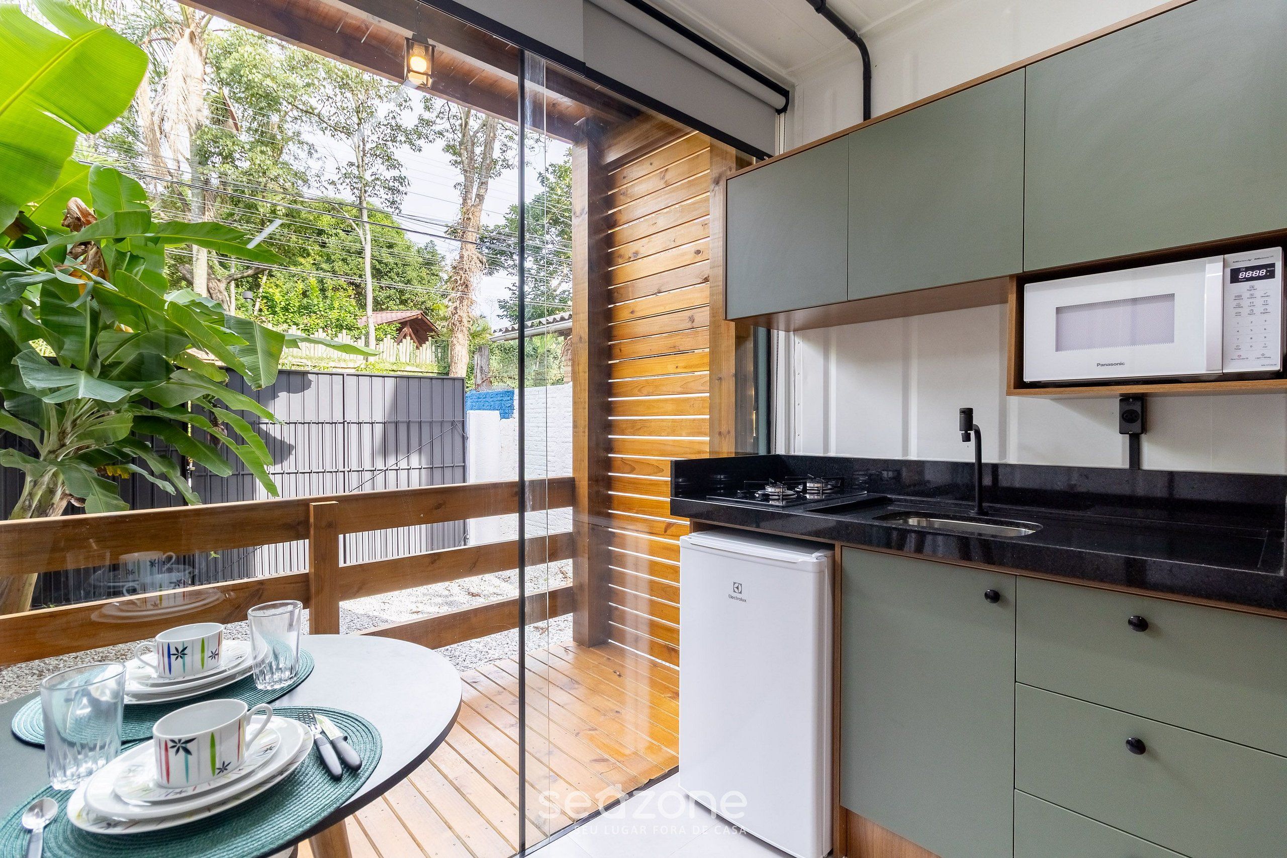 Una cocina moderna con microondas incorporado, un refrigerador pequeño y un comedor con una mesa preparada para dos.