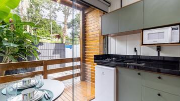 Una cocina moderna con microondas incorporado, un refrigerador pequeño y un comedor con una mesa preparada para dos.