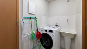 A compact bathroom with a washing machine, a sink, and a towel rack. - 2-bedroom Apartment in Asa Norte Nor0101 (Brasília)
