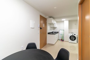 A compact kitchen with a washing machine, a stove, and a microwave. - Apart in Asa Norte, 750m From the Mall Nor0201 (Brasília)
