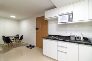 A modern kitchen with white cabinets, a black countertop, and a built-in microwave. - Apart in Asa Norte, 750m From the Mall Nor0201 (Brasília)
