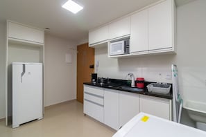 A compact kitchen with white cabinets, a microwave, a refrigerator, and a coffee maker. - 1BR Apartment, Self-checkin, Asa Norte Nor0202 (Brasília)