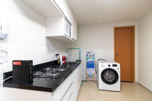 A compact kitchen with a gas stove, a microwave, and a washing machine. - 1BR Apartment, Self-checkin, Asa Norte Nor0202 (Brasília)