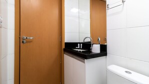 Un baño con puerta de madera, un lavabo con encimera negra y un inodoro.