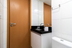 Un baño con puerta de madera, un lavabo con encimera negra y un inodoro.
