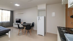 A modern kitchen with a gas stove, a white refrigerator, and a dining area with a table and chairs. - 1BR Fully Equipped Apartment, Asa Norte Nor0204 (Brasília)