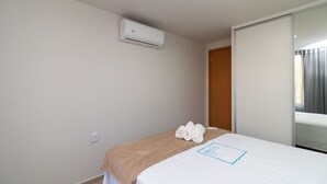 A hotel room with a bed, a brown blanket, rolled towels, an air conditioning unit, and a sliding door. - 1BR Fully Equipped Apartment, Asa Norte Nor0204 (Brasília)