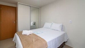 Ein Hotelzimmer mit einem Bett, einer Holztür, einem Spiegel und einer weißen Wand.