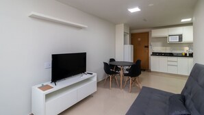 A modern living room with a flat-screen TV, a grey sofa, and a dining area with a small table and chairs. - 1BR Fully Equipped Apartment, Asa Norte Nor0204 (Brasília)