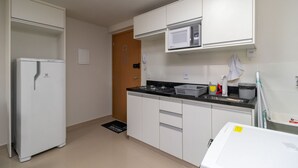 A compact kitchen with white cabinets, a built-in microwave, a stove, and a refrigerator. - 1BR Fully Equipped Apartment, Asa Norte Nor0204 (Brasília)