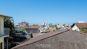 A residential area with terracotta-tiled roofs, a clear blue sky, and various buildings in the background. - Practical apt 550m fr Canasvieiras Beach Rtba1361 (Florianópolis)