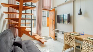 A modern interior with a staircase, a sofa, a dining table, chairs, and a TV.