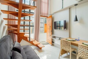 Un interior moderno con una escalera, un sofá, una mesa de comedor, sillas y un televisor.